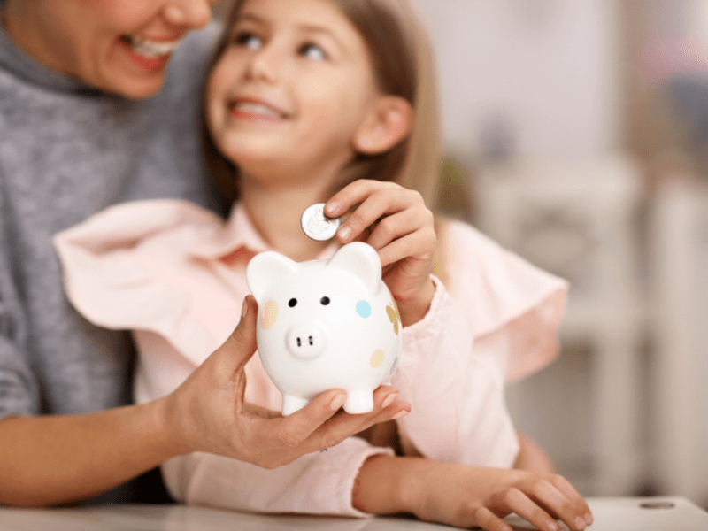 Young girl and her mother with a white piggybank
