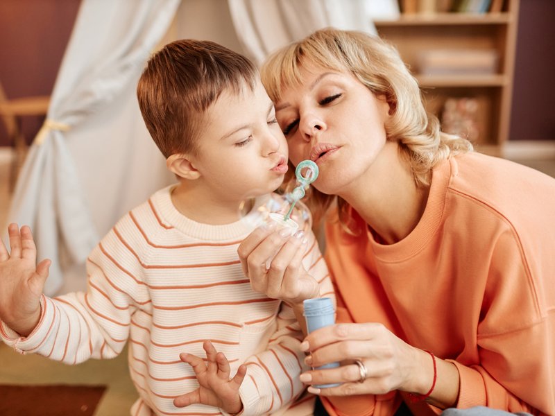 Mother and son with down syndrome blowing bubbles