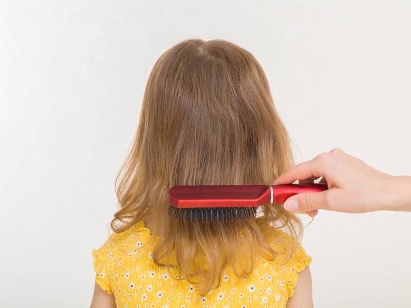 Mother combing daughter hair