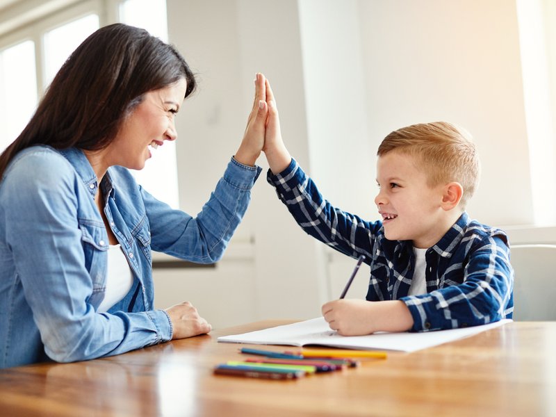 Mother helping child with studies while doing high five iStock