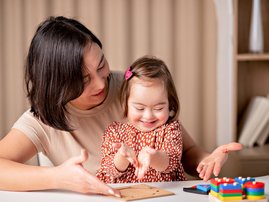 Mother helping her child with down syndrome with educational toys