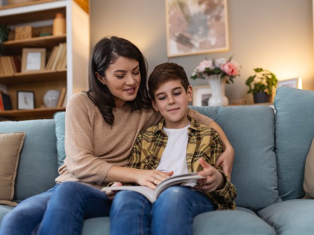 Mother reading book to son in living room