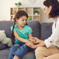 Mother sitting with daughter, holding her hands, talking to her and teaching her something