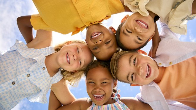 Multi Cultural Children Friends Linking Arms Looking Down Into Camera