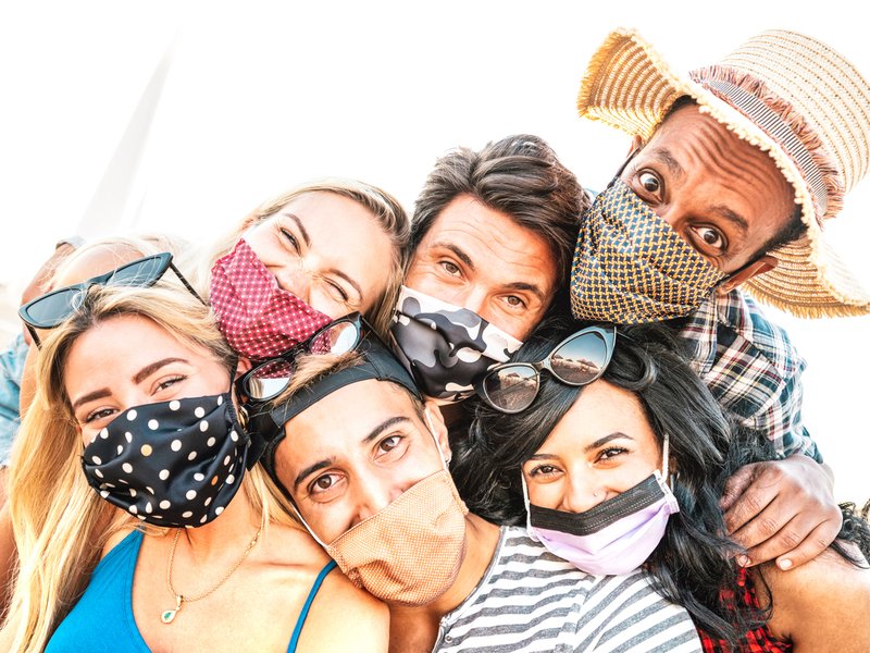 Multiracial milenial friends taking selfie smiling behind face masks