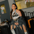 Nelly Furtado sits on a suitcase in a backstage dressing room area