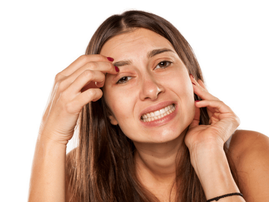 Nervous young woman has an itch on her face