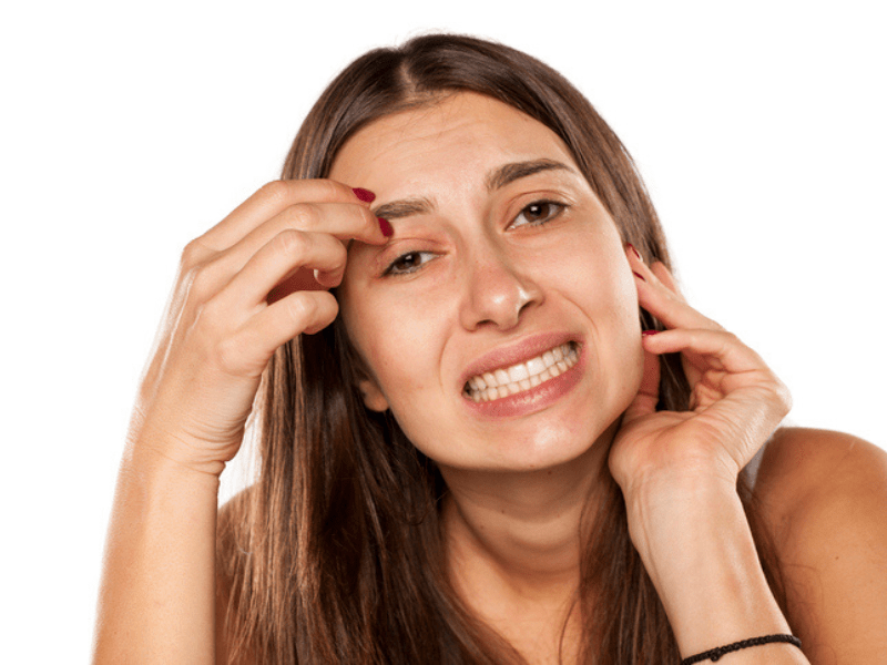 Nervous young woman has an itch on her face