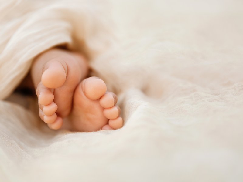 Newborn baby feet closeup on soft cream wrap