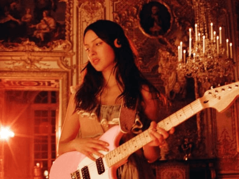 Olivia Rodrigo playing a pink guitar