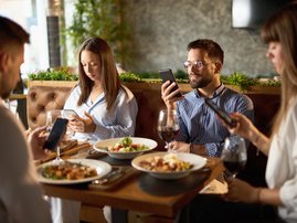 PEOPLE ON PHONES AT DINNER TABLE
