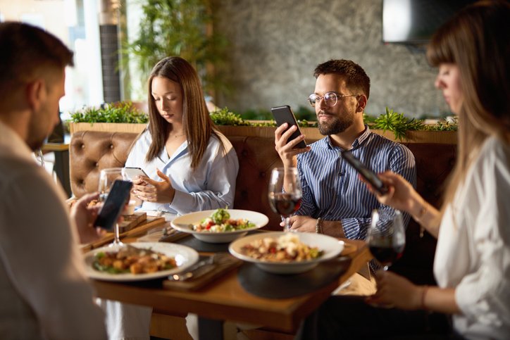 PEOPLE ON PHONES AT DINNER TABLE