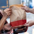 PERSON HANDING FAST FOOD THROUGH WINDOW