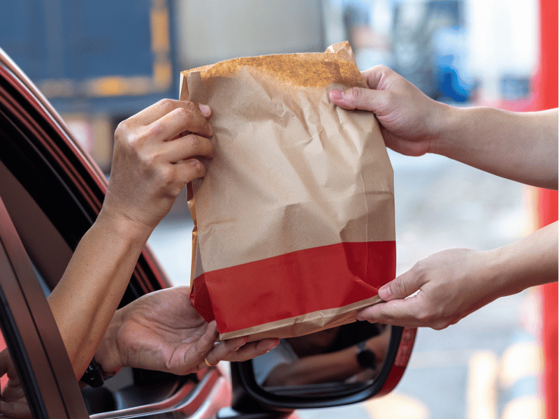 PERSON HANDING FAST FOOD THROUGH WINDOW