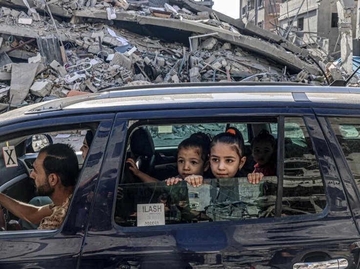 Palestinians drive amid the rubble of buildings destroyed in an Israeli air strike in Rafah, on the southern Gaza Strip