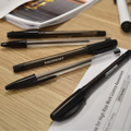 Papers and pens are spread on a desktop in an office