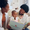 Parents reading book with child in home