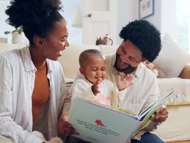 Parents reading book with child in home