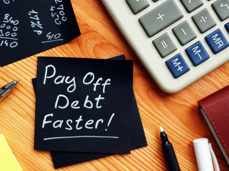 Pay off debt faster handwritten on a memo with calculator next to the memo pad