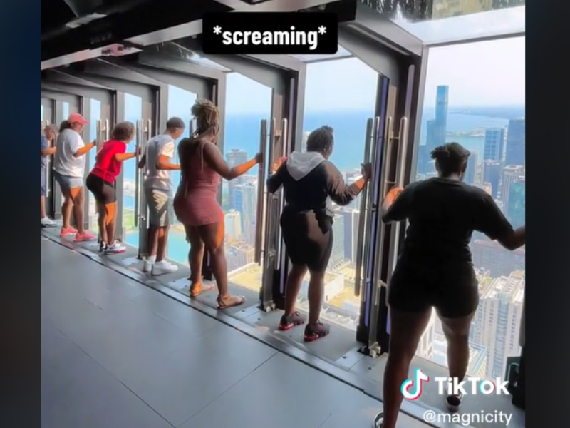 People are standing close to large windows at TILT ride