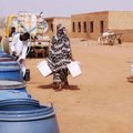 People fill water containers at a free distribution point