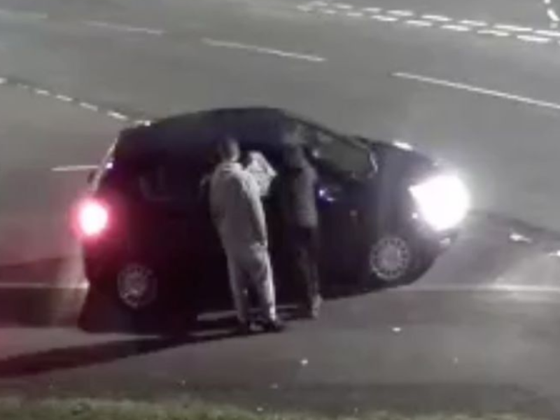 People standing at the window of a parked vehicle