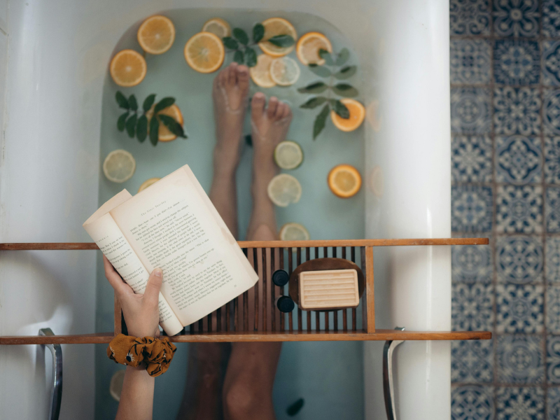 Person holding a book while soaking in the bath tub