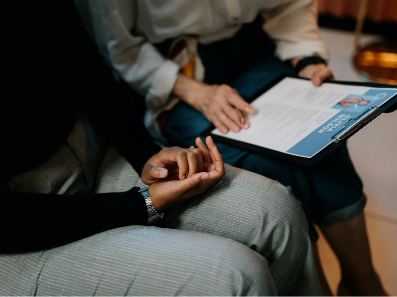 Person holding a clipboard with a resume having a discussion with another person