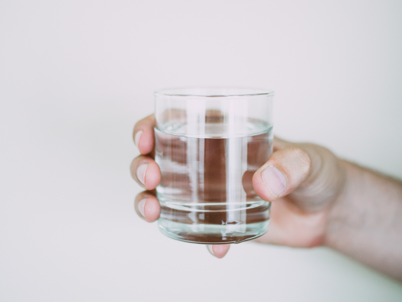 Person holding drinking glass with water