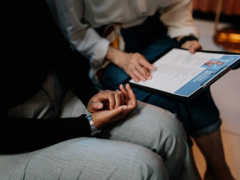Person in white long sleeve shirt holding clipboard with resume