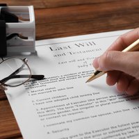 Woman signing Last Will and Testament at wooden table