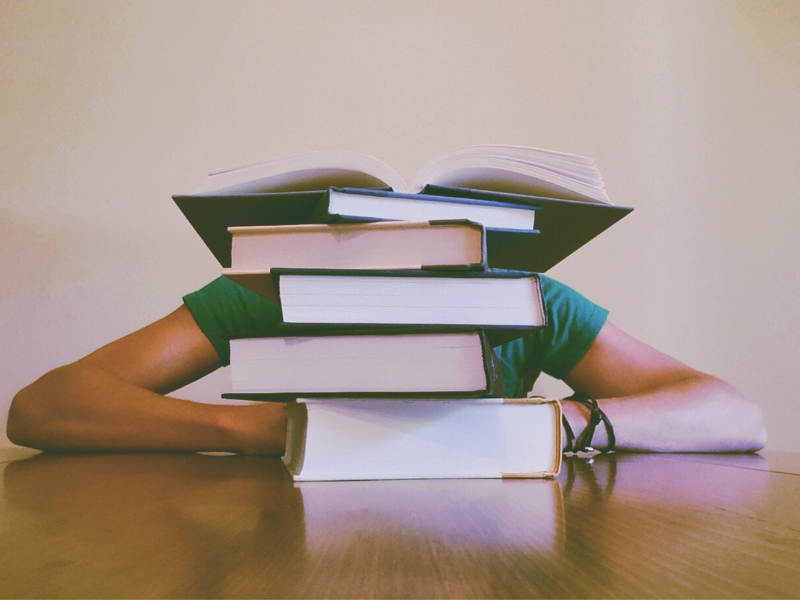 Person sitting behind a heap of books