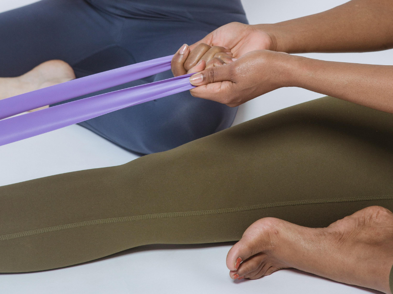 Person stretching resistance bands on legs while sitting on the floor