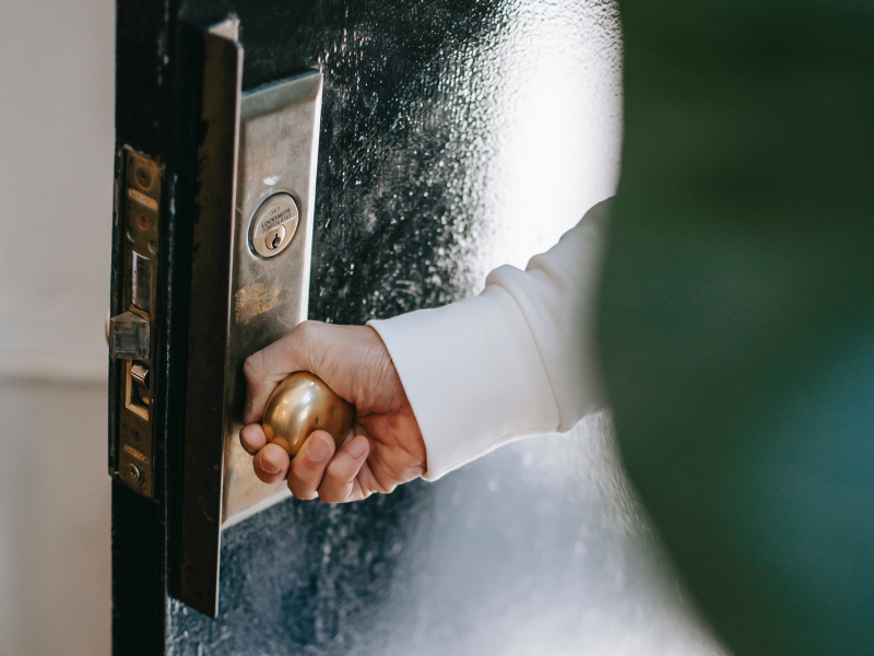 Person turning door handle while entering home