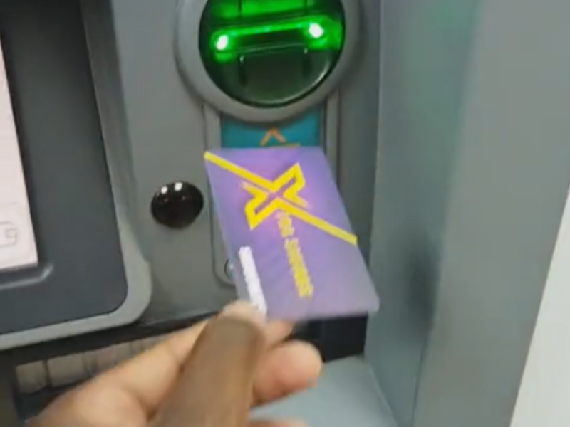 Person's hand feeding card into the ATM