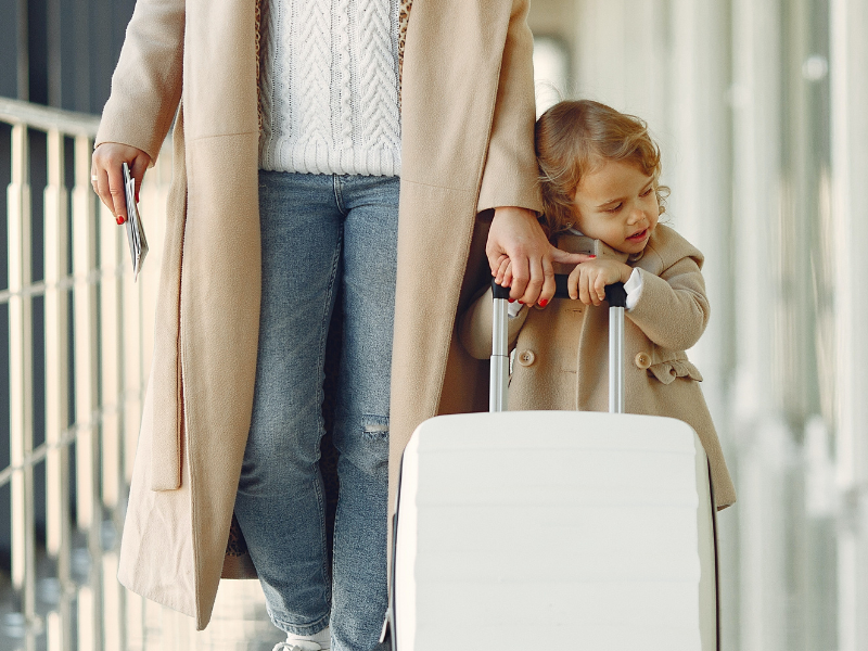 Positive mother and daughter with suitcase in airport