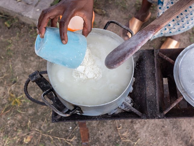 Pouring corn and cassava flour into a pot