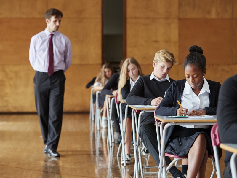 Teenage Students Sitting Examination With Teacher