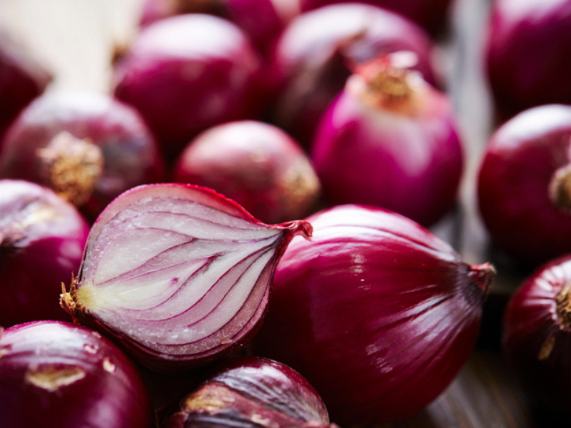 Red onions lay together in a bundle
