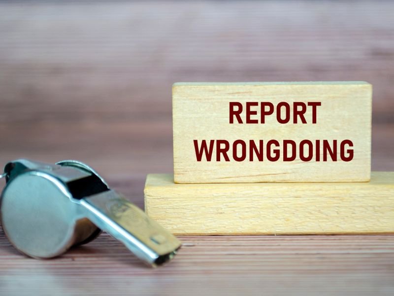 Report Wrongdoing text on wooden blocks with whistle