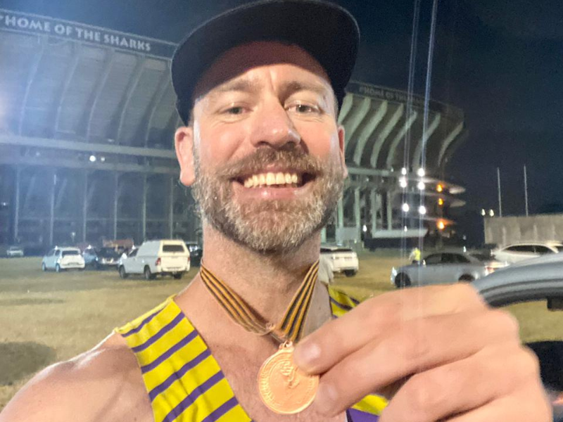 Rory Petzer smiling while holding his Comrades medal