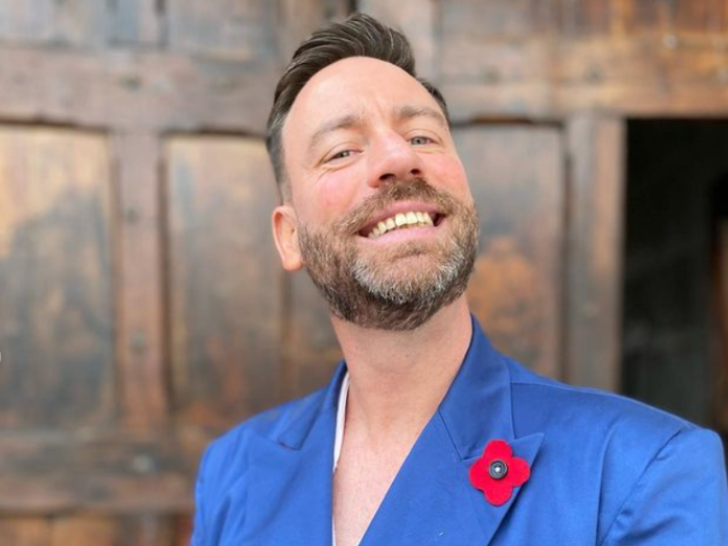 Rory Petzer posing with a blue satin blazer