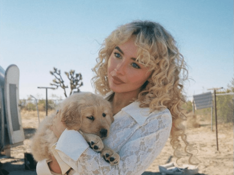 Sabrina Carpenter carrying a golden retriever puppy