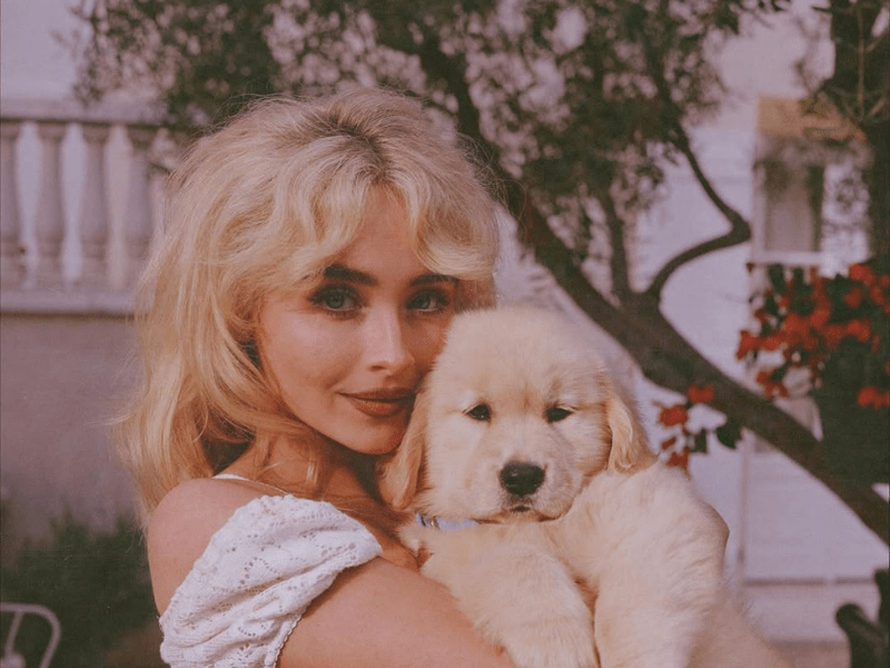 Sabrina Carpenter posing with a golden retriever puppy