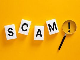 Scam word with magnifying glass identifying fraud and warning