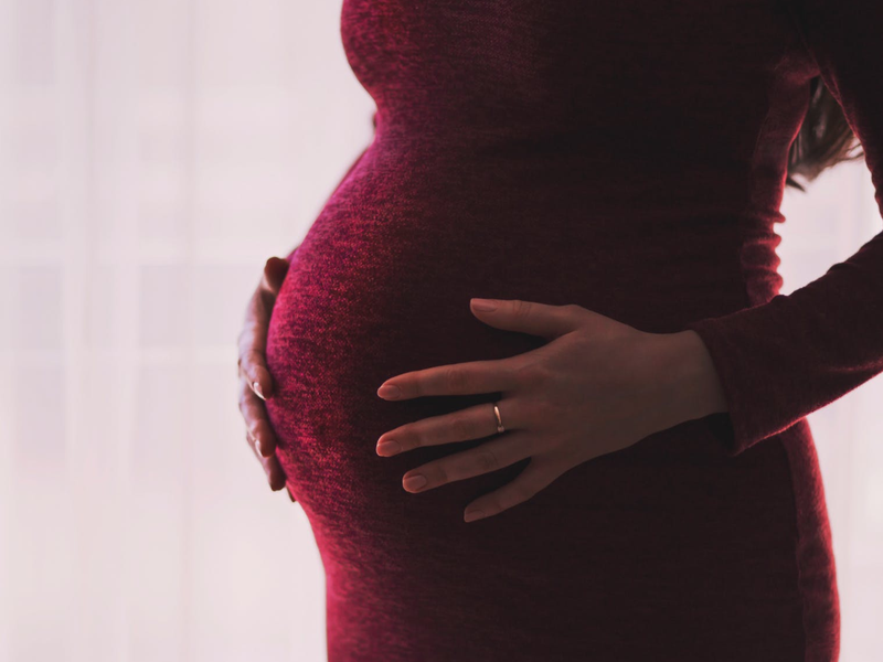 Pregnant woman holding her stomach / Pexels