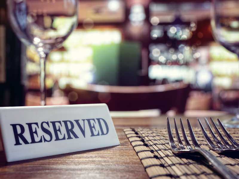 Reserved sign on restaurant table with bar background / iStock