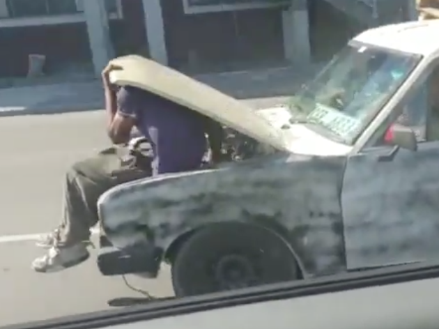 Man works on moving car engine