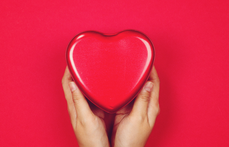 Woman holding red heart on red background / iStock