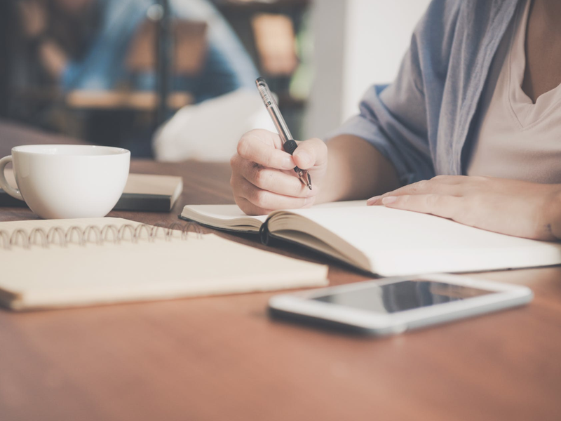 Businesswoman writing in a book / Pexels